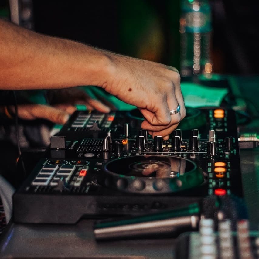 Mão do DJ ajustando a controladora durante um evento