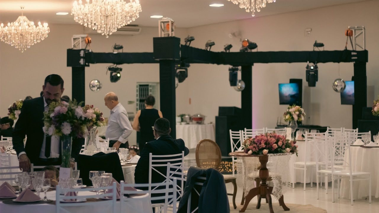 Salão de festa com mesas decoradas e a estrutura de iluminação montada